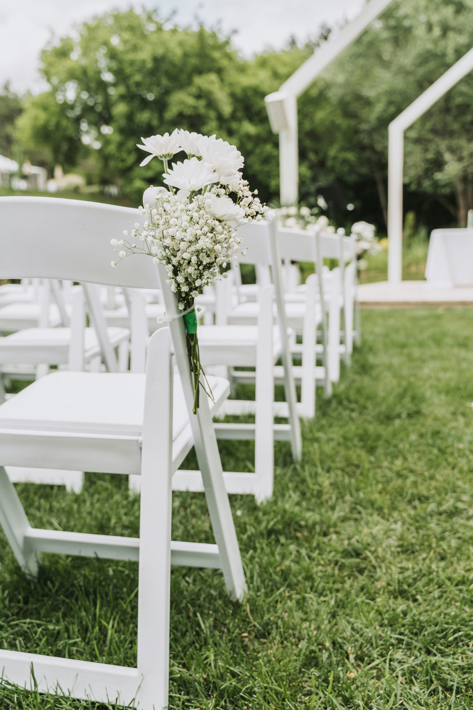 White folding chairs lined up on the lawn for an outdoor wedding ceremony
