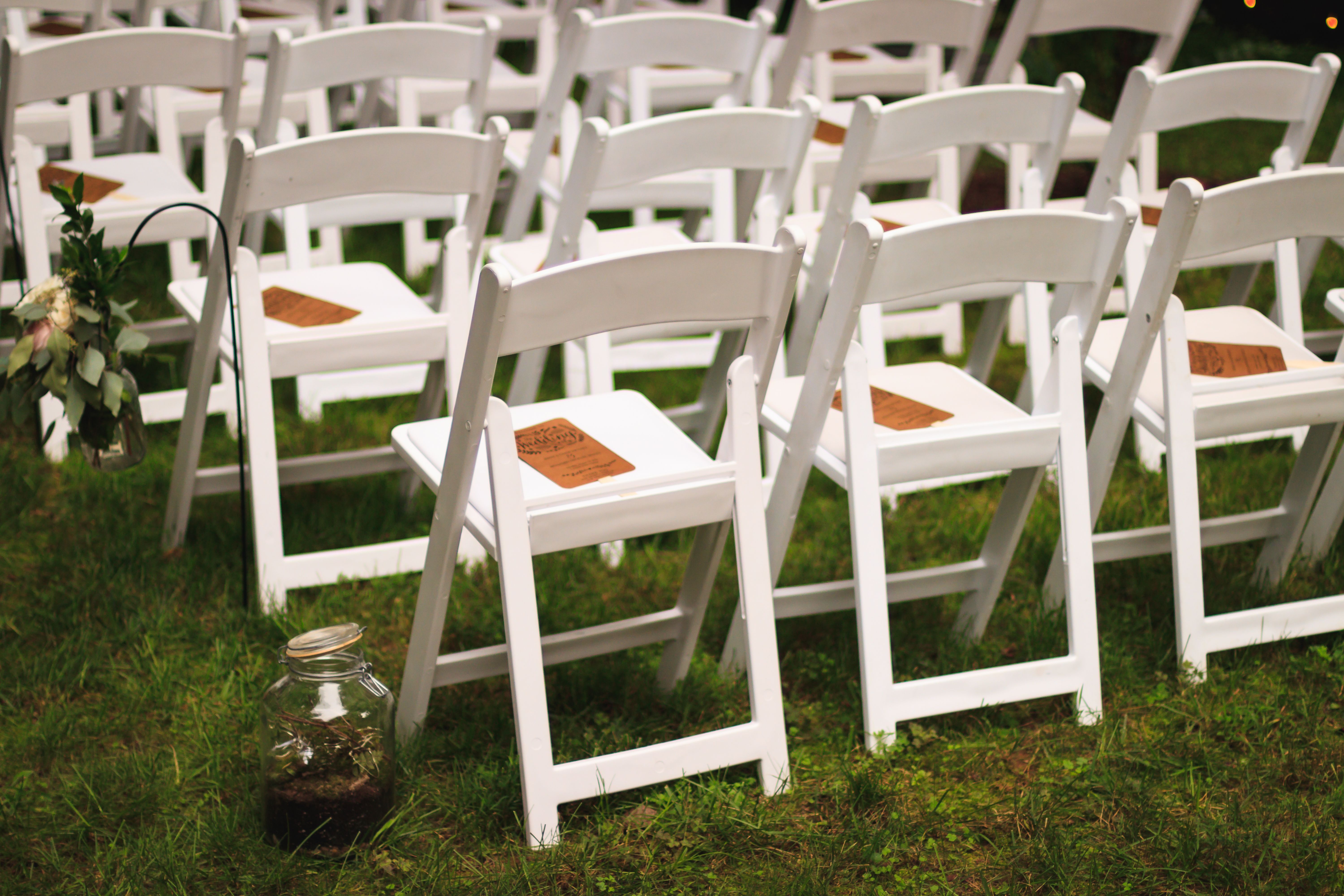 White folding chairs glowing under string lights at an evening outdoor event