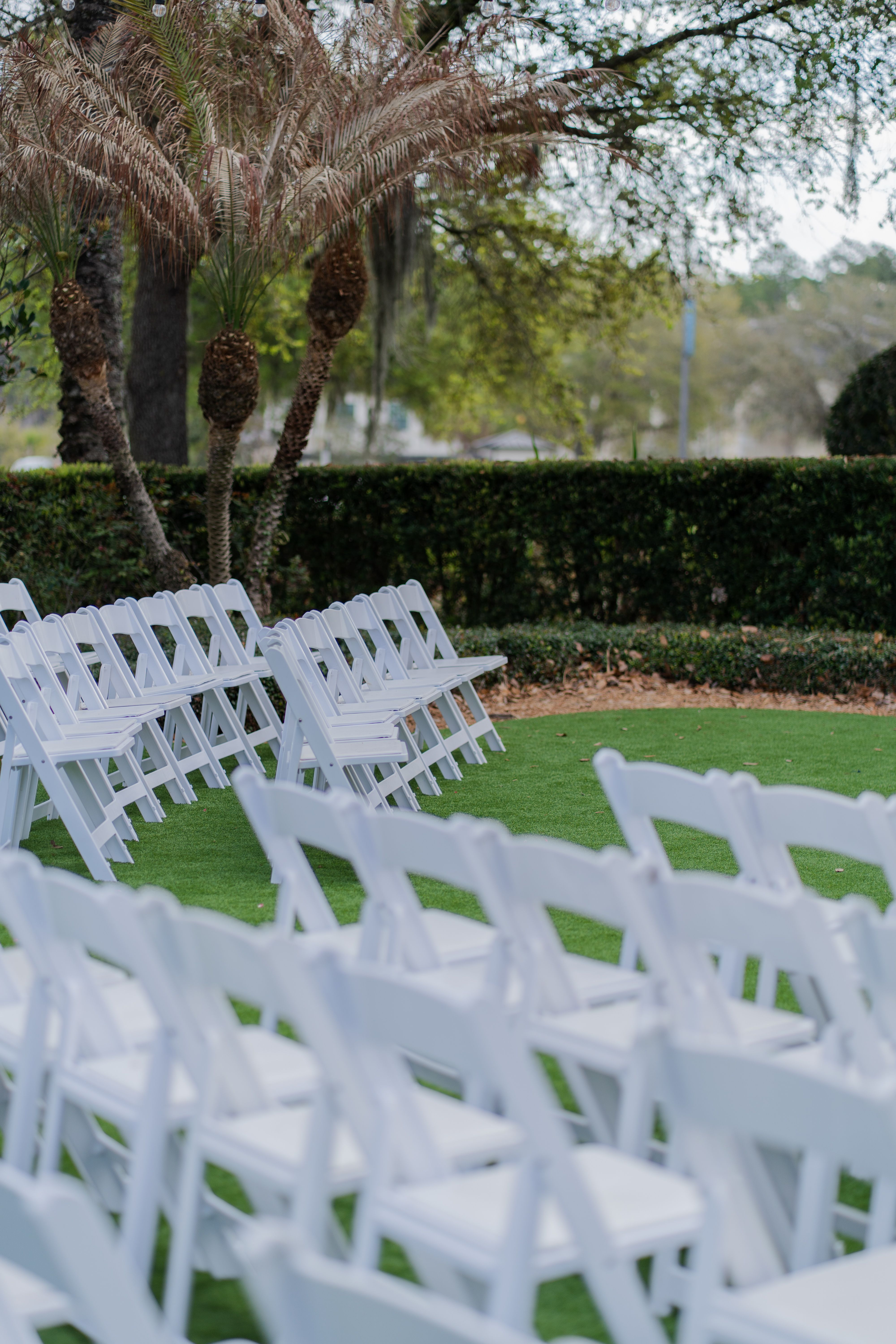 White folding chairs set up in a landscaped outdoor courtyard