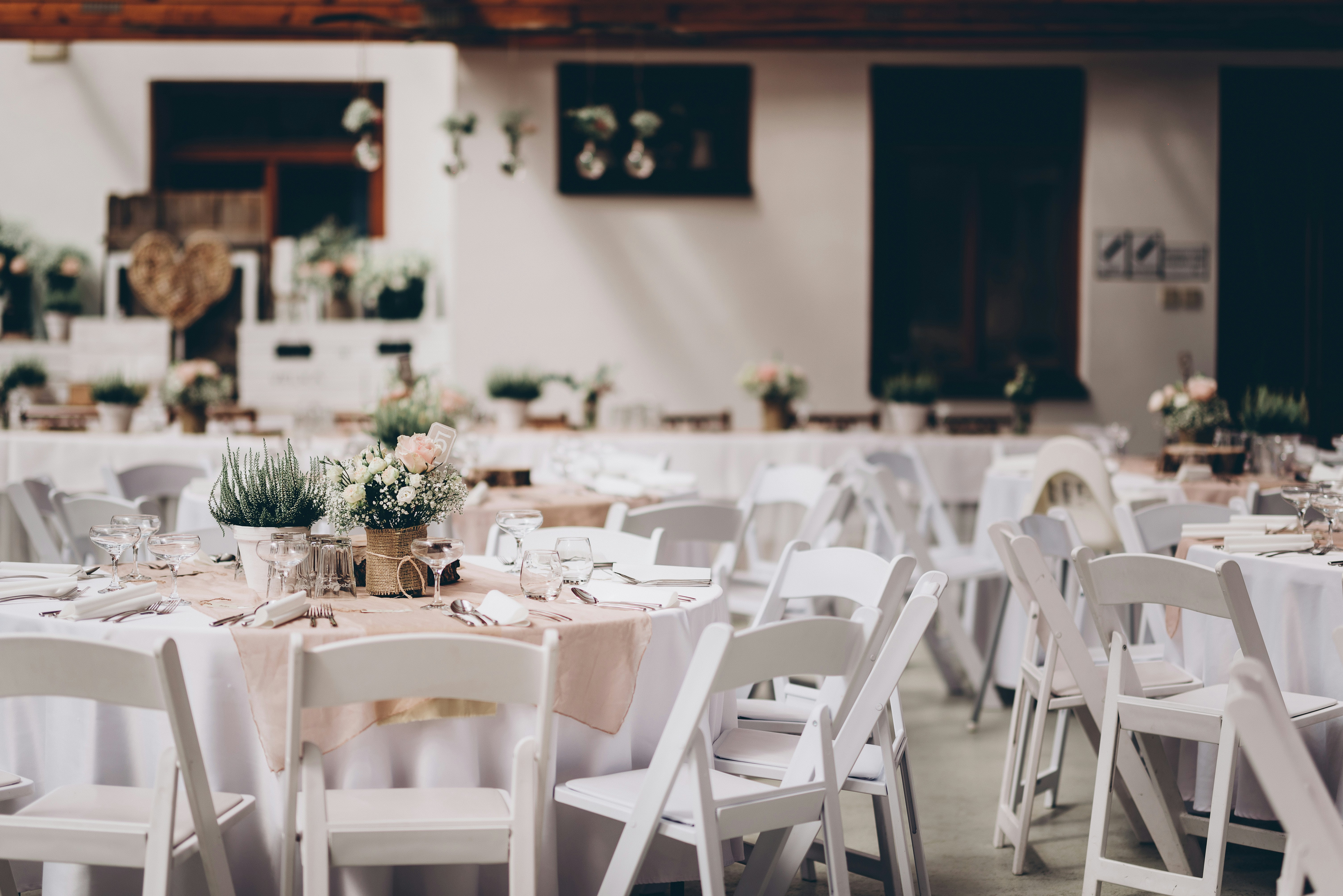 Round reception tables with white linens and floral centerpieces set for a wedding reception